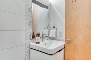 A bathroom with a white sink, a mirror, and two bottles of shampoo. - Centric 2 BR Condo - Roma - Rio de Janeiro Park (Mexico City)