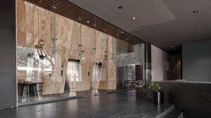 En moderne lobby med glasvæg, receptionsdisk og trappe.
