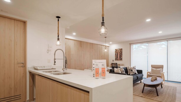 Una cocina moderna con armarios de madera, una isla central e iluminación colgante.