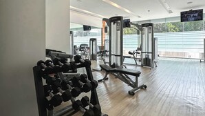Une salle de sport équipée de matériel de musculation, de machines de cardio et d’un écran de télévision.