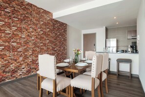 Ein Essbereich mit Backsteinwand, Holztisch und vier Stühlen.