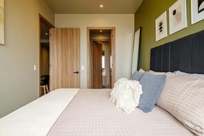 A bedroom with a bed, a wardrobe, a door leading to another room, and a wall with framed pictures. - Amazing 1 BR Condo in Reforma - Pool - Gym - King (Mexico City)