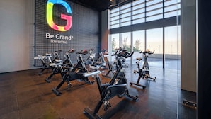Uma academia com bicicletas ergométricas e um grande logotipo na parede.