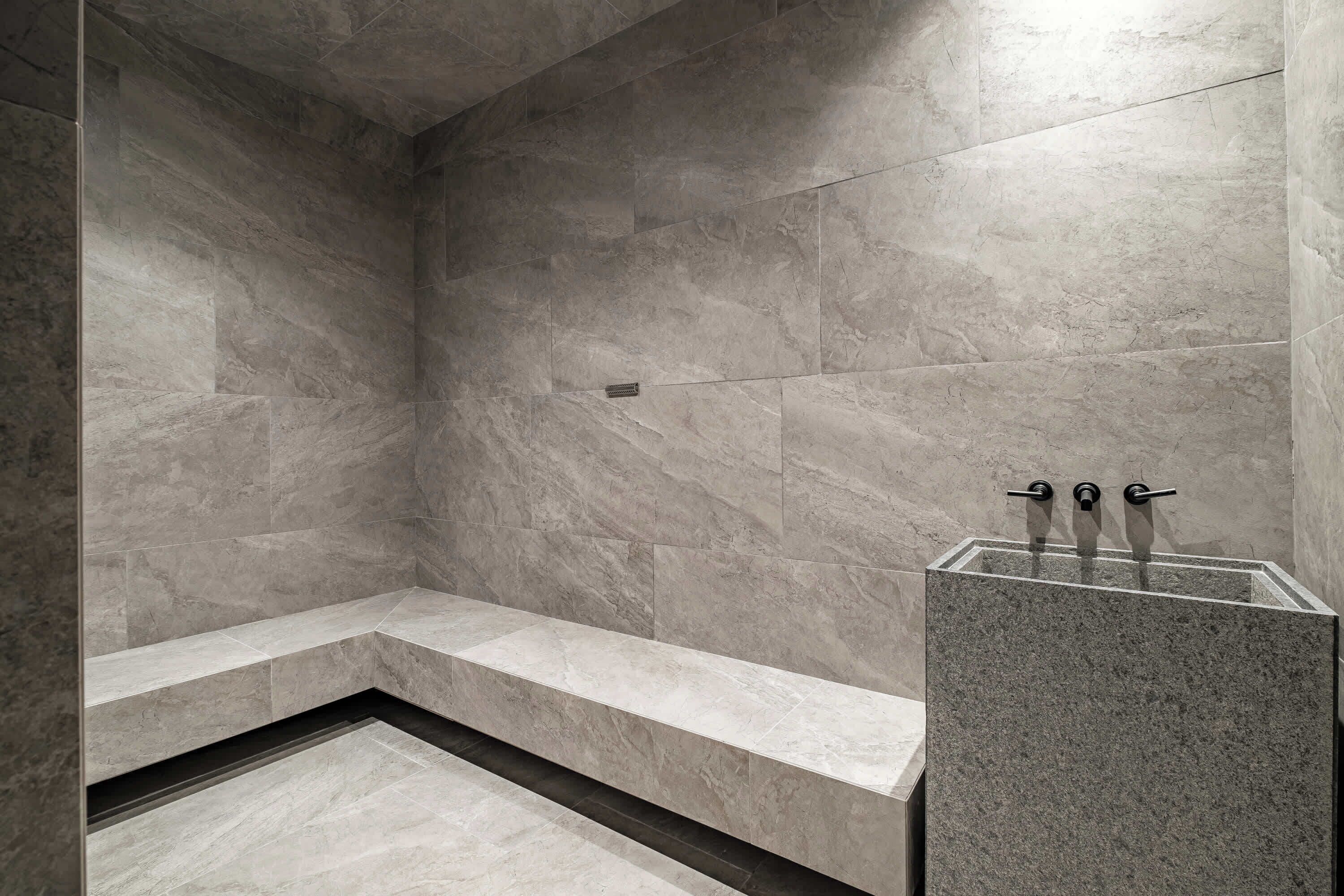 A modern bathroom with a built-in bench and a glass pedestal sink.