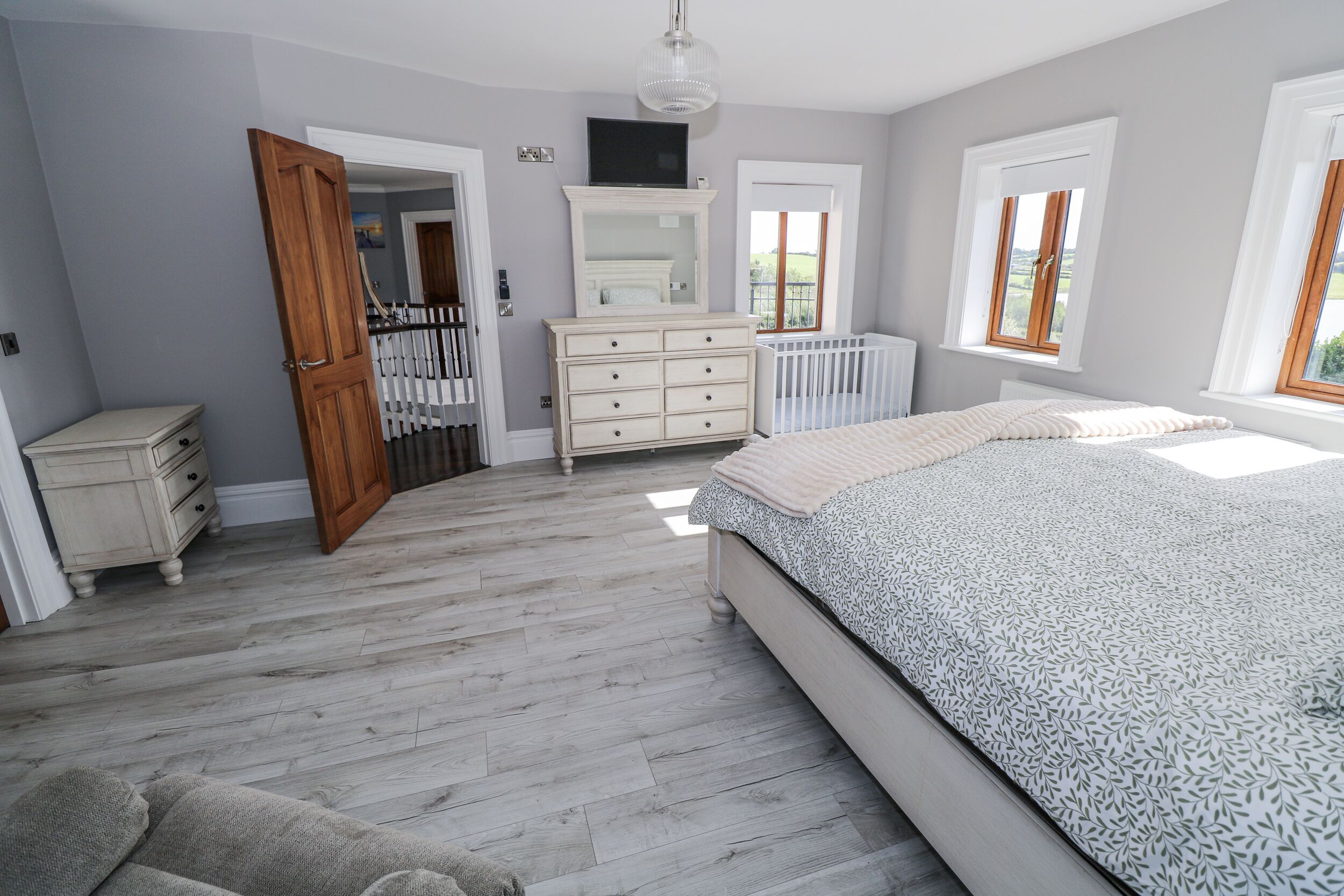 A bedroom with a large bed, a dresser, a mirror, and a window.