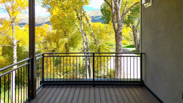 Un balcon offrant une vue sur les arbres aux couleurs automnales et un paysage montagneux.