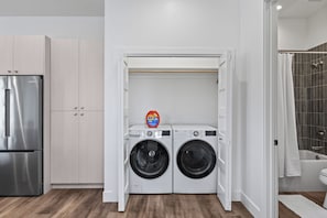 A compact kitchen with a stainless steel refrigerator, a washing machine, and a dryer. - Steamboat Monthly Rental | Furnished Condo by Yampa River | Free Bus Route (Steamboat Springs)