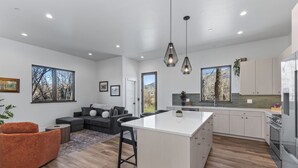 Une cuisine moderne avec des meubles blancs, un îlot central et des luminaires suspendus.