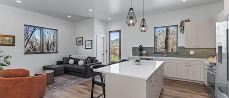 A modern kitchen with white cabinets, a central island, and pendant lighting.
