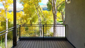 En balkon med udsigt til efterårsfarvede træer og et bjerglandskab.