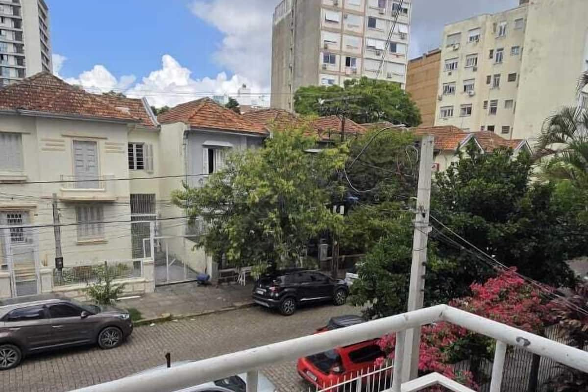 Een balkon met uitzicht op een woonstraat, inclusief geparkeerde auto's en gebouwen.