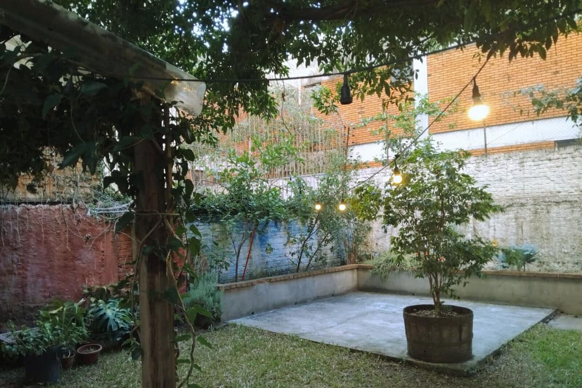 Een binnenplaats met een betonnen vloer, plantenbakken en lichtjes.