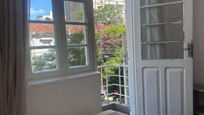Een kamer met een bed, een raam en een deur naar een buitenruimte.