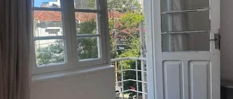 A room with a bed, a window, and a door leading to an outdoor area.