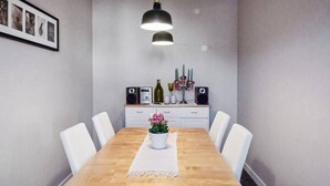 A dining area with a wooden table, white chairs, a white cabinet with speakers and a radio, and a framed picture on the wall. - 3 bedroom cozy apartment in Finspång (Finspång)