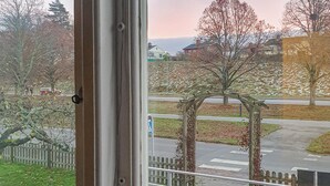 A view through a window with a wooden fence, a pedestrian crossing, and leafless trees. - 3 bedroom cozy apartment in Finspång (Finspång)