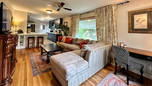 Ein gemütliches Wohnzimmer mit Sofa, Couchtisch und Essbereich, im Hintergrund eine Küche.