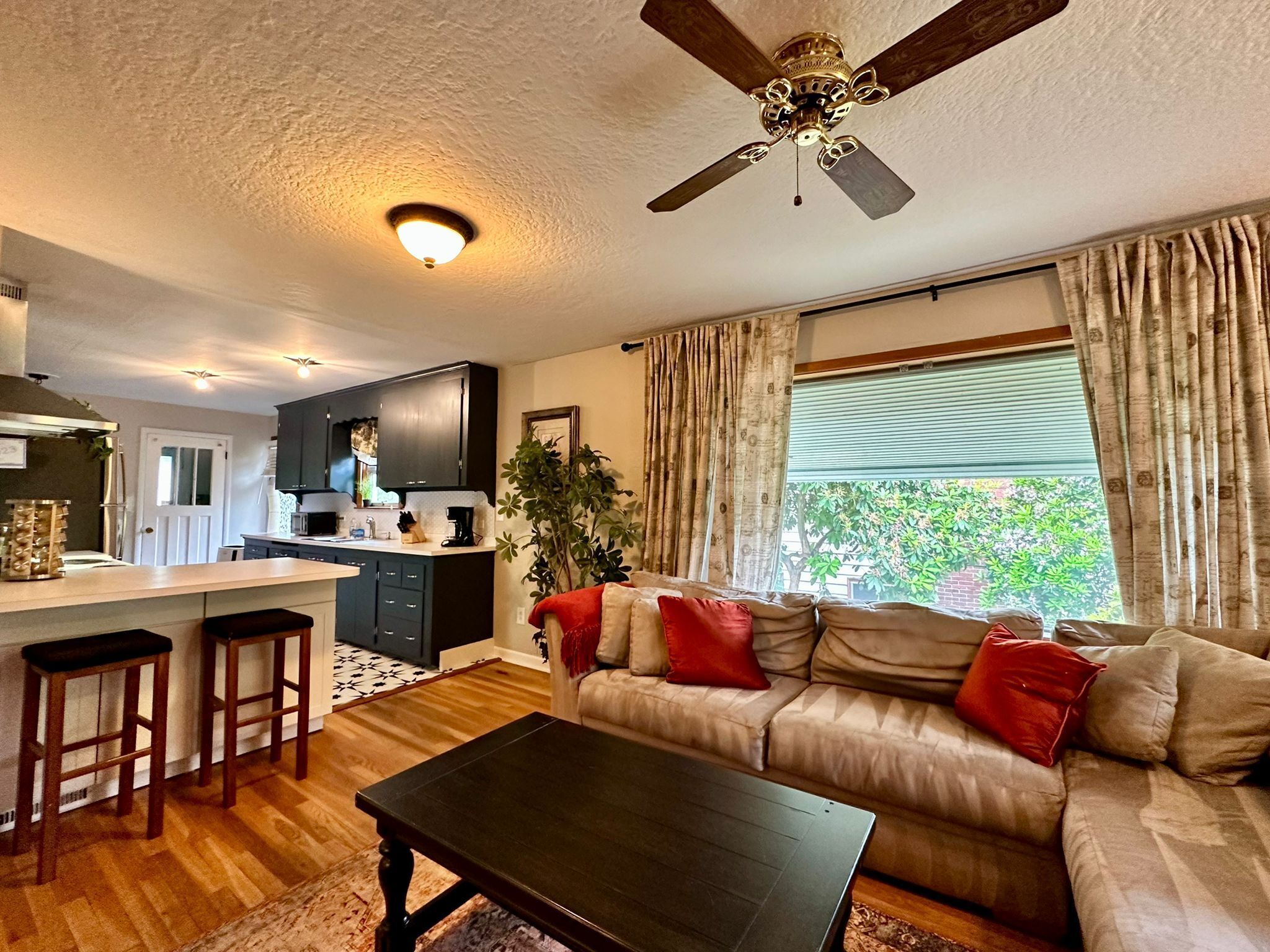 Une cuisine moderne avec des meubles de couleur sombre, un îlot central et un ventilateur de plafond.