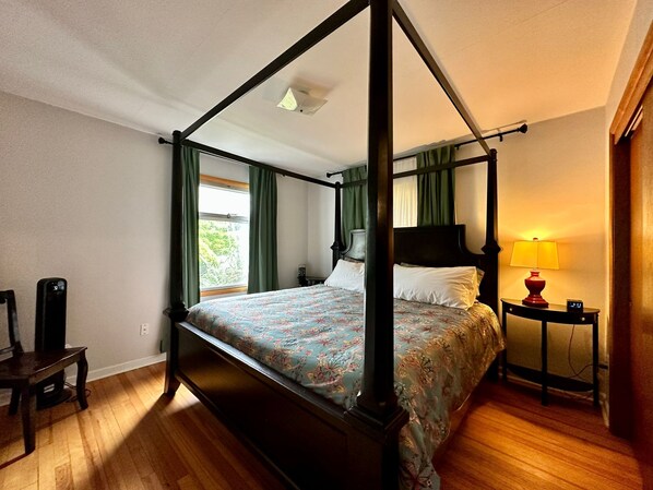A four-poster bed with a floral bedspread, a bedside table with a lamp, and a chair. - Seattle's Starlight Bungalow  (Seattle)