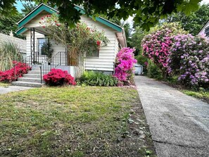 A house with a front porch, steps leading to the entrance, and a garden with various plants and flowers. - Seattle's Starlight Bungalow  (Seattle)