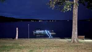 Ein Nachtblick auf einen Seeuferpark mit einer anlegenden Mole, einem Weg, der zur Mole führt, und einer Bank unter einem Baum.