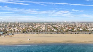 A coastal cityscape with a wide beach, clear skies, and a distant view of a city center. - Steps to Beach & 2nd St. Retreat, Hot-Tub, Parking, 3BR w/Private Studio (Long Beach)