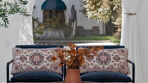 A cozy seating area with a patterned sofa, a round wooden table, and a potted plant. - Steps to Beach & 2nd St. Retreat, Hot-Tub, Parking, 3BR w/Private Studio (Long Beach)