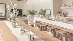 Een moderne keuken met houten aanrechtbladen, barstoelen en hangende rieten hanglampen.