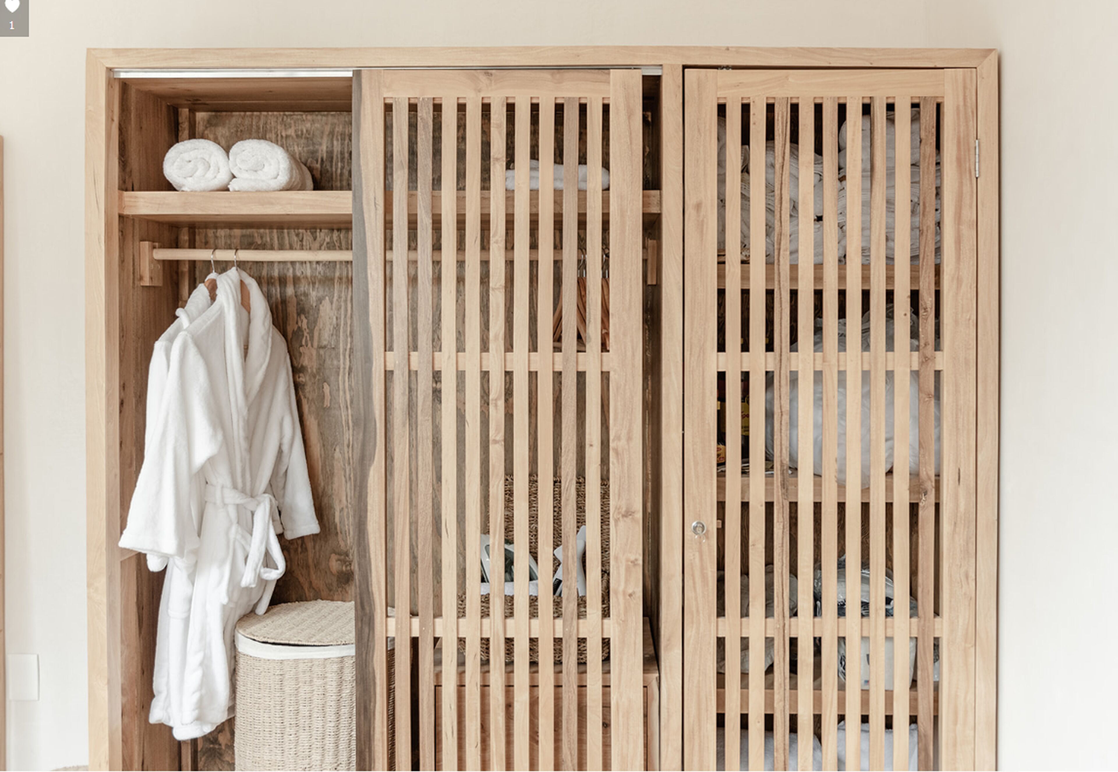 A wooden wardrobe with a woven basket and a white robe hanging on the left.