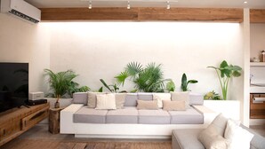 Een moderne woonkamer met een bank, houten balken en potplanten.