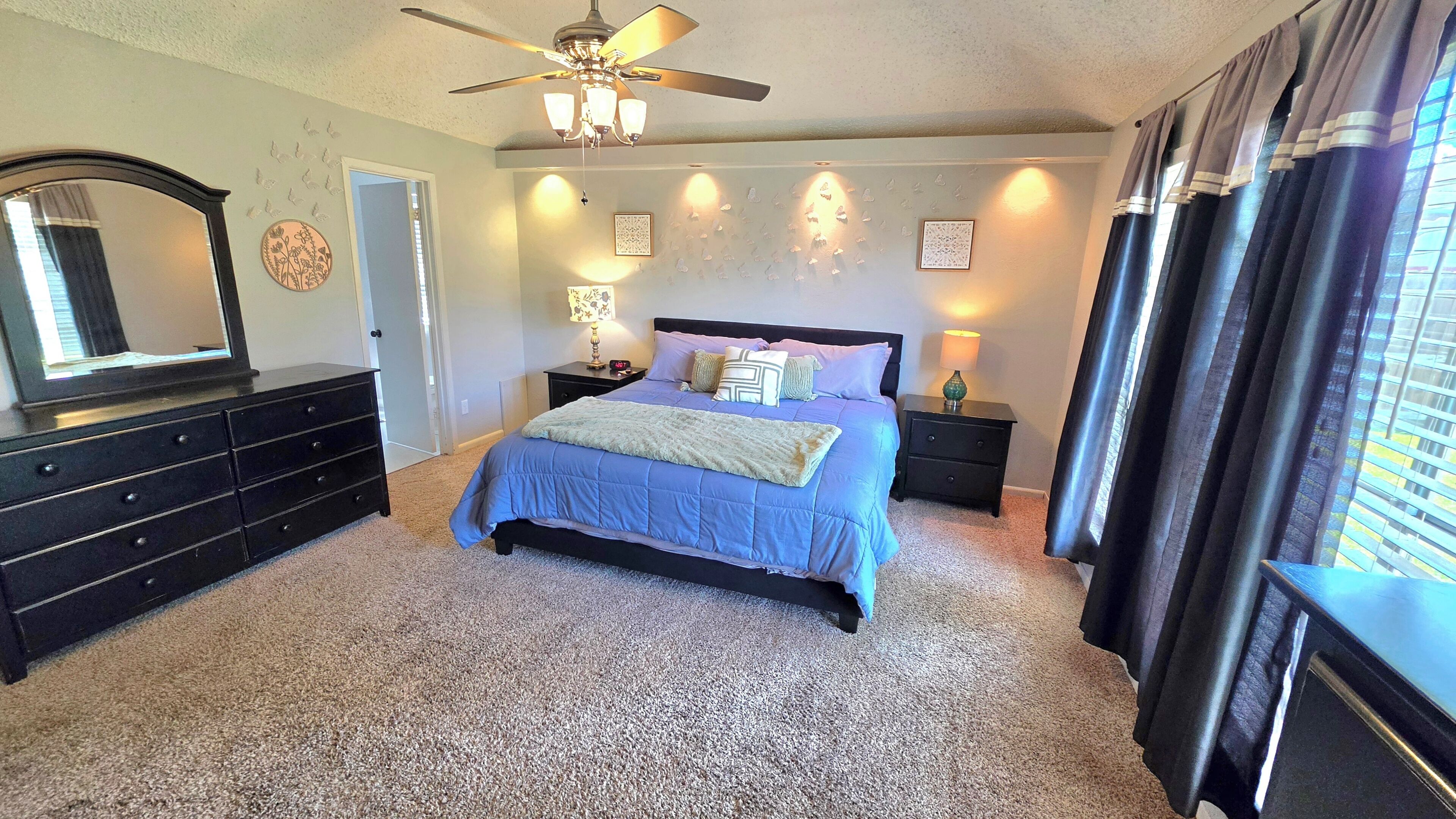 A bedroom with a bed, dresser, nightstands, and a ceiling fan.