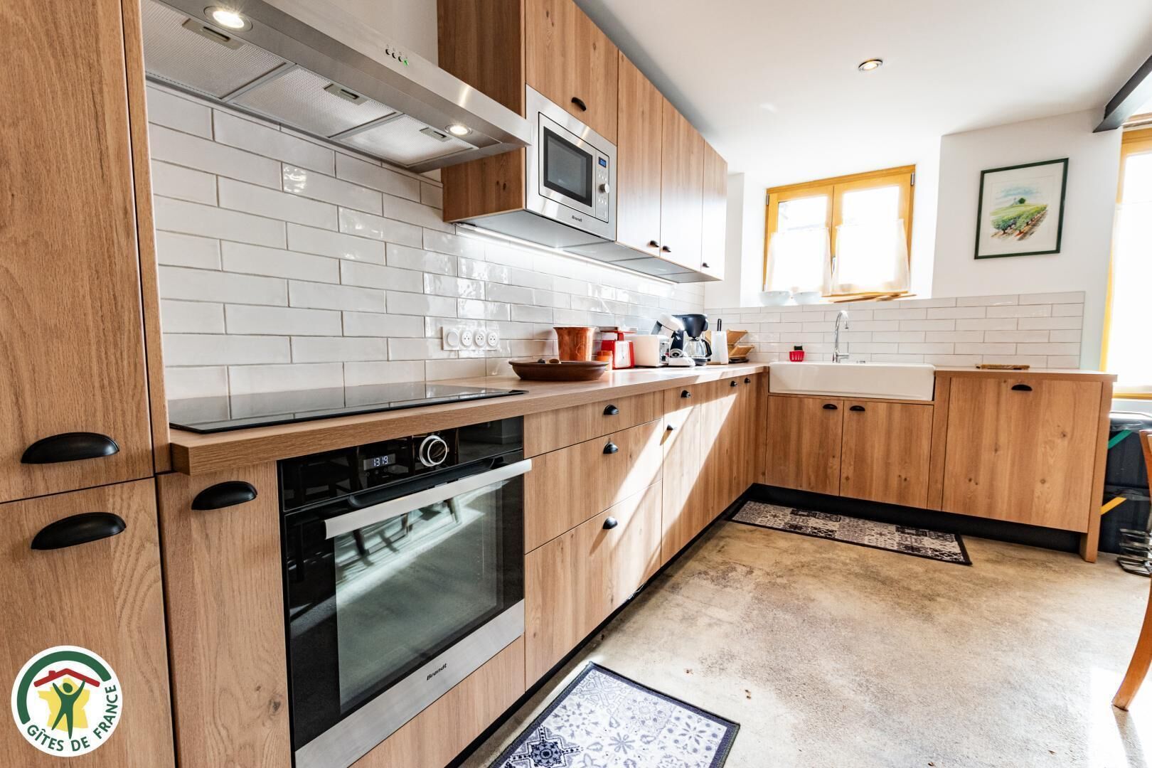 Een moderne keuken met houten kastjes, een inbouwoven en een magnetron.
