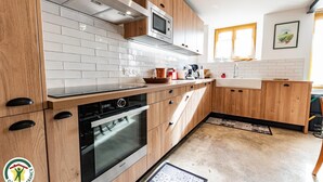 Moderni keittiö, jossa on puiset kaapit, sisäänrakennettu uuni ja mikroaaltouuni.