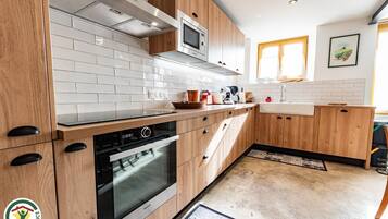 Een moderne keuken met houten kastjes, een inbouwoven en een magnetron.