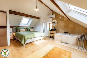 A bedroom with a skylight, a large bed, a bedside table, and a nightstand. - Le Cellier Roze Gîte - VERZY (VERZY)