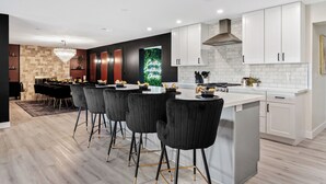 Een moderne keuken met een centraal eiland, witte kasten en een eethoek met zwarte stoelen.
