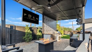 Een terras buiten met een vuurkorf, zitplaatsen en een barbecue.