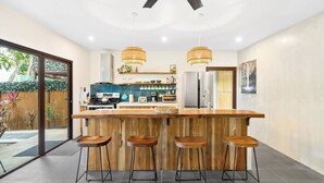 Eine moderne Küche mit einer zentralen Kochinsel, Barhocker und einem Deckenventilator.
