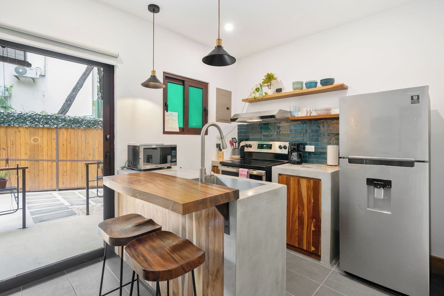 A modern kitchen with a wooden island, stainless steel appliances, and a large refrigerator.