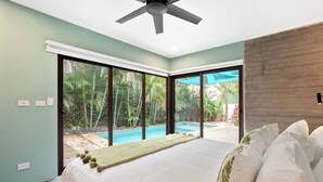Ein Schlafzimmer mit einem großen Bett, einem Deckenventilator und Blick auf einen Swimmingpool.