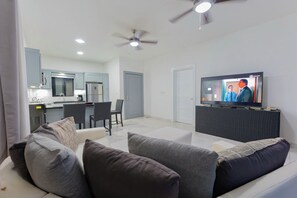 A modern living room with a sofa, a television, and a kitchen area in the background. - Private Pool Villa in Gated Casa Linda, Near Sosua Beaches (Sosúa)