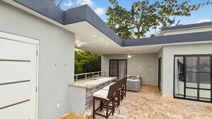 Um pátio moderno ao ar livre com área de bar, assentos e piscina.