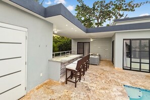 A modern outdoor patio with a bar area, seating, and a pool. - Private Pool Villa in Gated Casa Linda, Near Sosua Beaches (Sosúa)