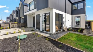 Un moderno edificio residencial de varios pisos con grandes ventanales y un jardín cuidado.
