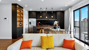 Una cocina moderna con armarios de madera oscura, un refrigerador de acero inoxidable e iluminación colgante.