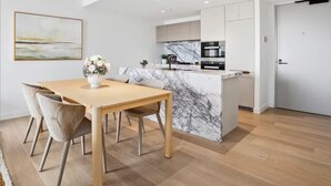 Une cuisine moderne avec des comptoirs en marbre, un coin repas avec une table et des chaises en bois, et une porte blanche.