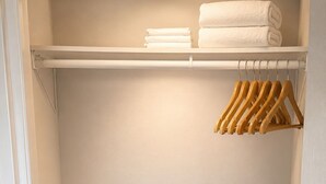 Un armario con suelo de madera, una puerta blanca y una percha con colgadores de madera.