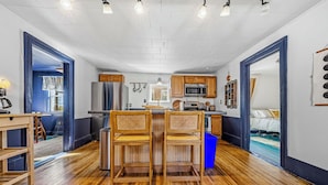 A compact kitchen with wooden chairs, a refrigerator, a microwave, and a sink.