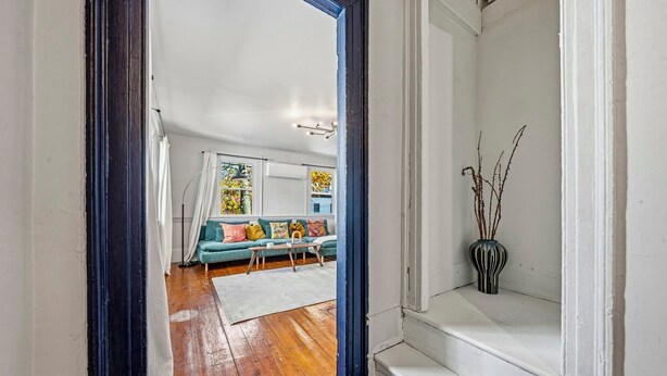 A living room with a sofa, a coffee table, and a vase on a windowsill.
