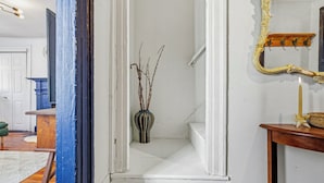 A staircase with white walls, a vase with branches, and a mirror with a gold frame.